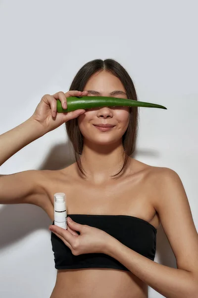 Sonriente joven asiático chica escondido detrás de aloe hoja — Foto de Stock