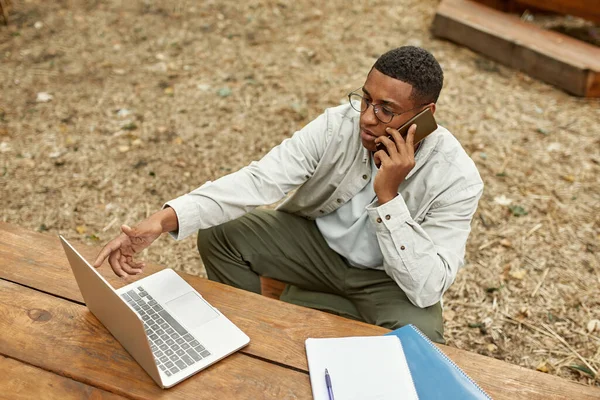 Junger Afroamerikaner telefoniert in der Nähe von Laptop — Stockfoto