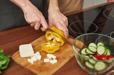 Erkek elleri salata için sarı biber kesiyor.