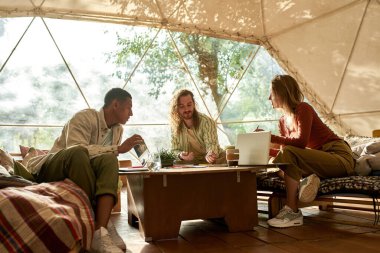 Genç çok ırklı iş arkadaşları birlikte çalışıyor ve konuşuyorlar.