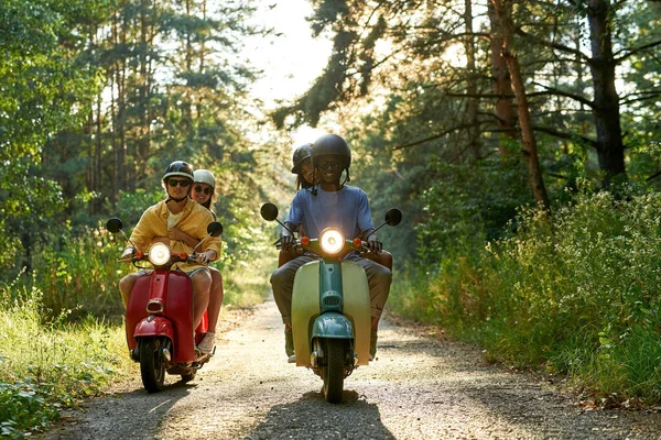 Sorrindo jovens amigos multirraciais montando scooters — Fotografia de Stock