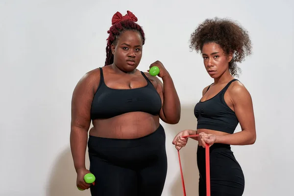 Picture of two afro women holding dumbbells and skipping rope, everybody can do sport — Stock Photo, Image