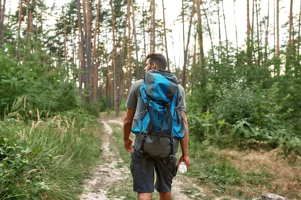 Man with tourist backpack trekking alone in summer forest — Stock Photo, Image