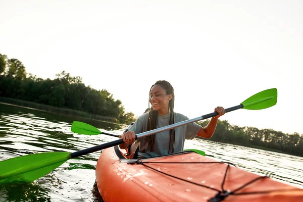 Jovencita alegre sonriendo, disfrutando de un día en kayak junto a su amiga en un lago en una tarde de verano —  Fotos de Stock