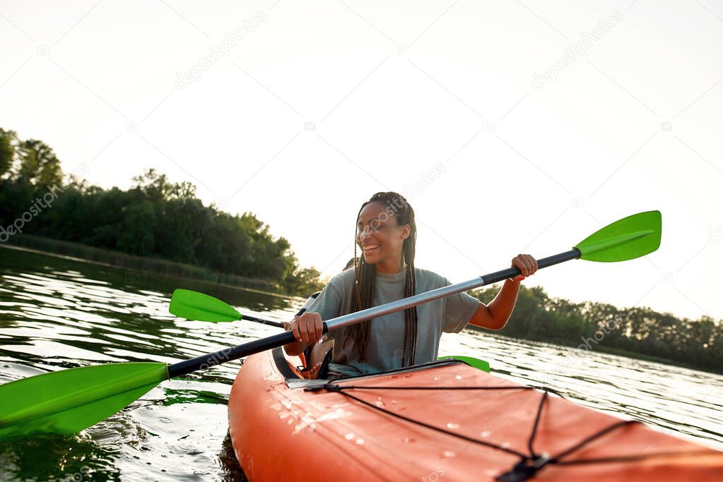 Joyful young woman smiling, enjoying a day kayaking together with her friend in a lake on a late summer afternoon