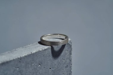 Gri arkaplanda izole edilmiş beton elementte gümüş halkanın makro çekimi