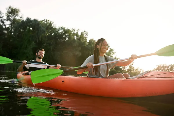 Felice giovane donna e il suo ragazzo godendo kayak insieme in un lago in un pomeriggio di fine estate — Foto Stock