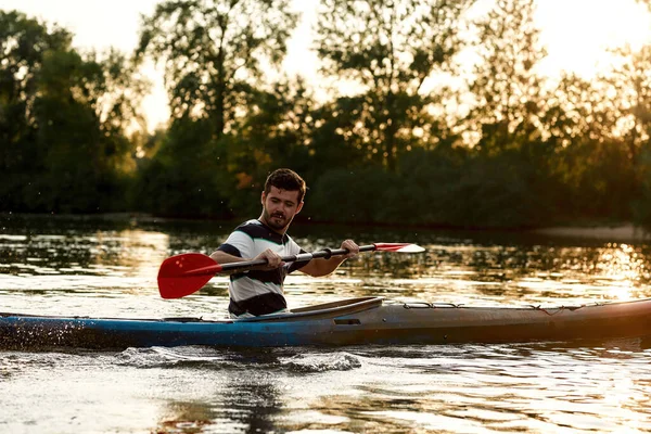 Vrolijke jonge Kaukasische man heeft plezier tijdens het kajakken op een meer midden in de natuur — Stockfoto