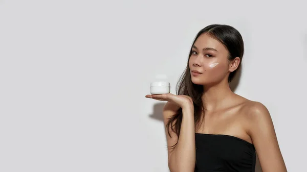 Joven asiática chica holding cosmetological crema en palma — Foto de Stock