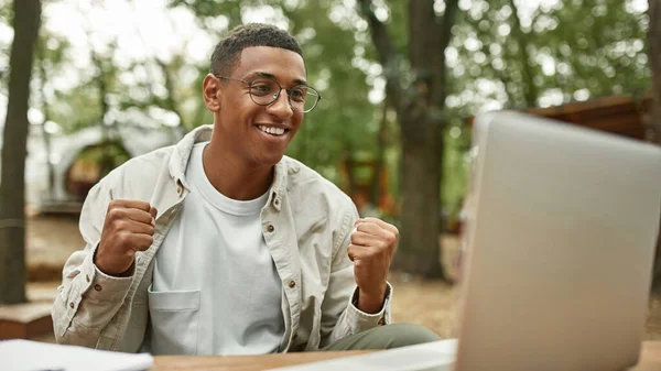 Lächelnder junger Afroamerikaner vor Laptop — Stockfoto