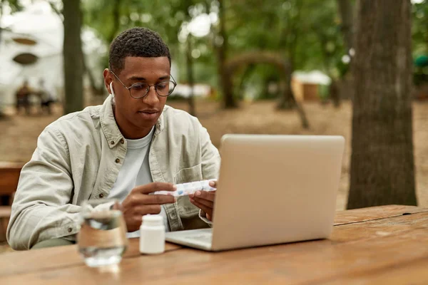 Joven afroamericano hombre celebración semanal píldora organizador — Foto de Stock