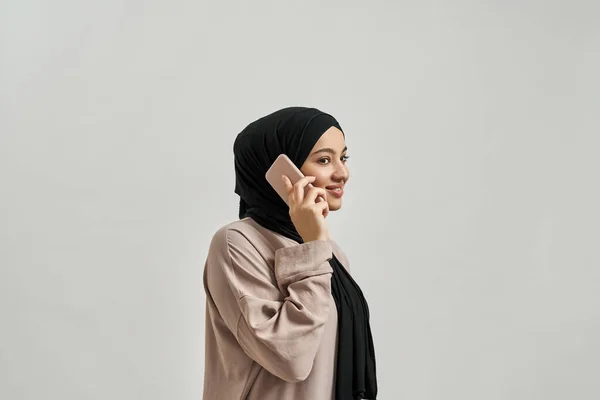 Sorridente ragazza araba in hijab parlando su smartphone — Foto Stock