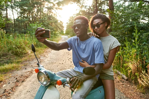 Sonriente afroamericano joven y chica montando scooter — Foto de Stock