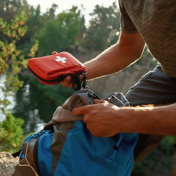 Jovem tirando kit de primeiros socorros da mochila — Fotografia de Stock