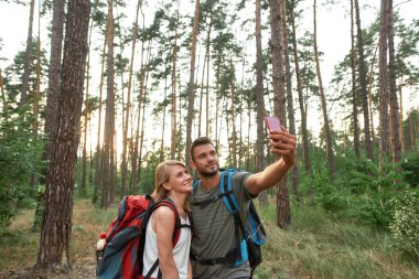 Neşeli genç beyaz çift ağaçta selfie çekiyor.