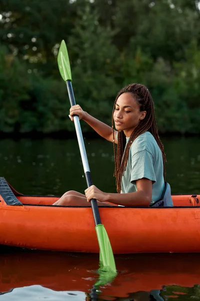 Attraktive junge Frau sieht beim Paddeln mit dem Kajak auf einem See inmitten der Natur entspannt aus — Stockfoto