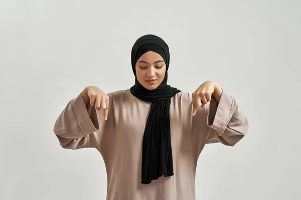 Весела арабська жінка в хіджабі вказує пальці вниз — стокове фото