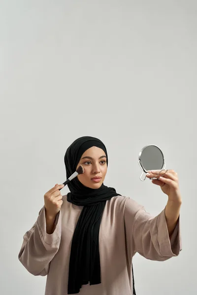 Νεαρή αραβίδα γυναίκα με μαντίλα που εφαρμόζει καλλυντικά — Φωτογραφία Αρχείου