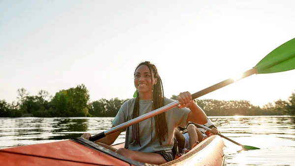 Actieve jonge vrouw glimlachen, genieten van een dag kajakken samen met haar vriend in een meer op een late zomermiddag — Stockfoto