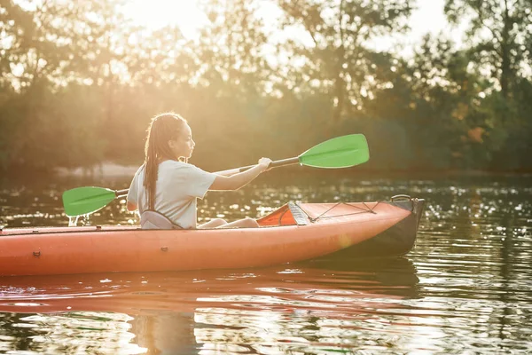 Actieve jonge vrouw kajakken op een meer omgeven door prachtige natuur op een zomerse dag — Stockfoto