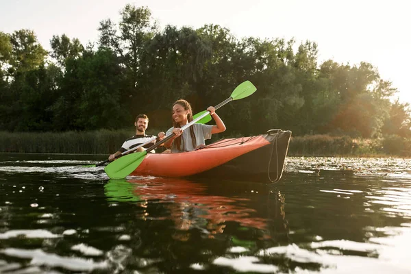 Giovane coppia di amici che si divertono, in kayak in un fiume immerso nella splendida natura in una giornata estiva — Foto Stock