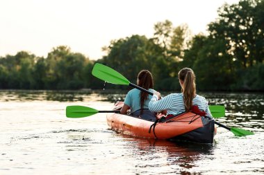 Adventurous young women boating together on a lake surrounded by peaceful nature