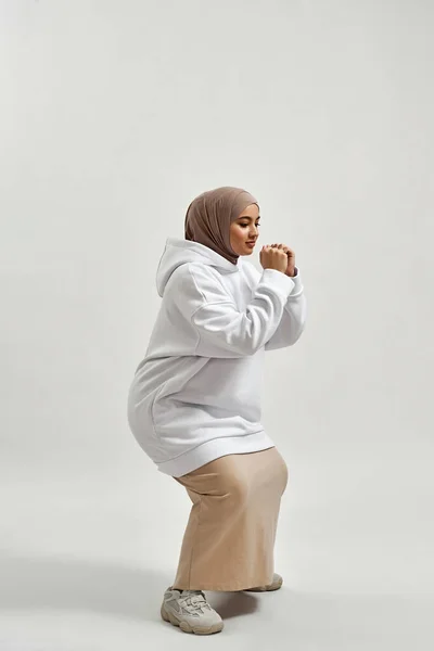 Cheerful young arabian woman in hijab doing squats — Foto Stock