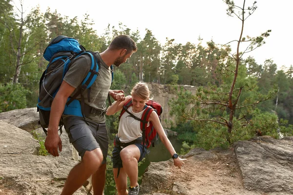 Happy young caucasian man and woman climbing rock — Photo