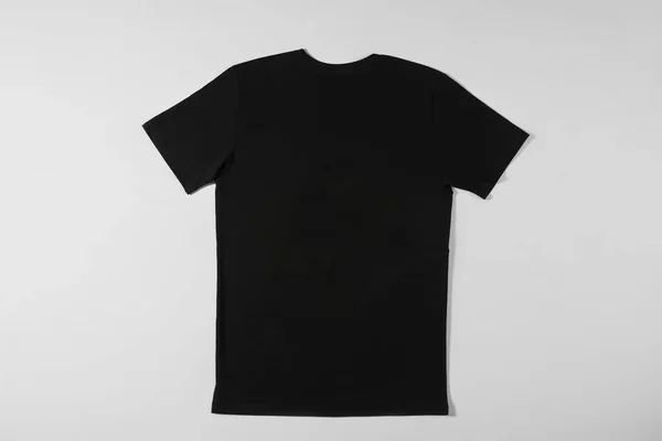 T-shirt preta deitada sobre um fundo branco — Fotografia de Stock