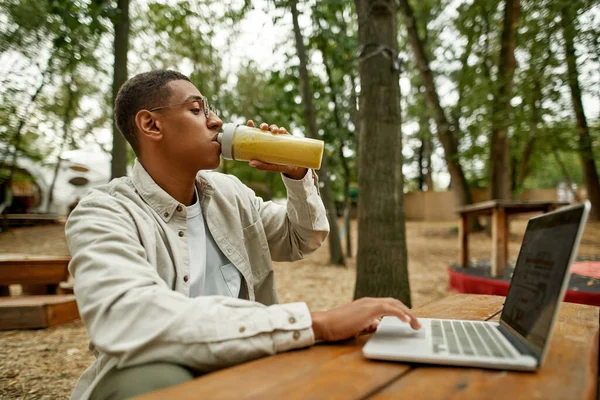 Junger afrikanisch-amerikanischer Freiberufler trinkt Saft — Stockfoto