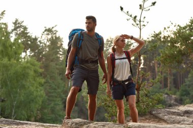 Cheerful young caucasian man and woman on rock