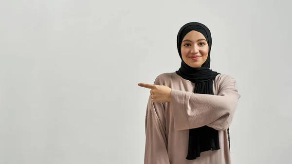 Щаслива молода арабська жінка в хіджабі вказує на бік — стокове фото
