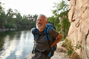 Back hurting middle aged caucasian man during trekking