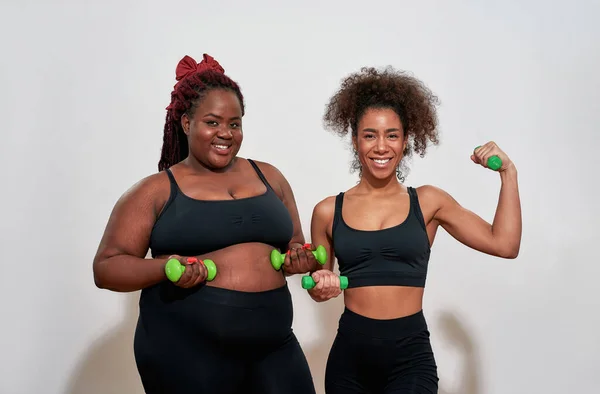 Picture of two afro women holding dumbbells and smiling in camera — Foto Stock