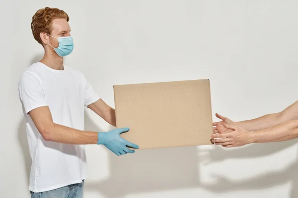 Young deliveryman gives a cardboard box to the customer