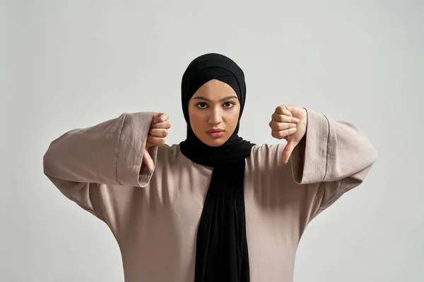 Upset young arabian woman in hijab showing thumb down — Stock Fotó