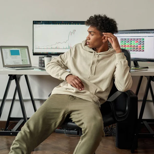 Disappointed young guy, investor analyzing stock charts, looking at laptop screen, sitting at desk, trading online from home — ストック写真