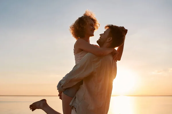 Happy young caucasian man holding cheerful woman up — Stock Photo, Image