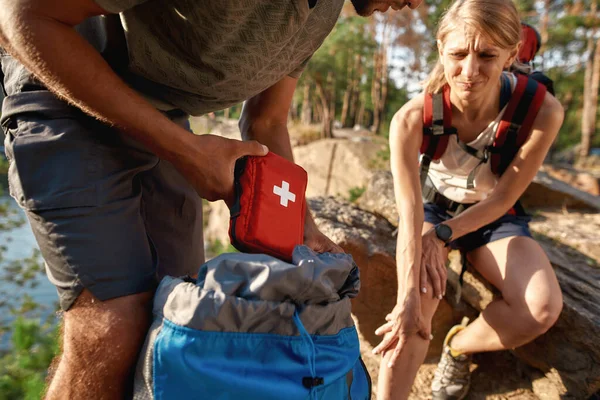 Young man using first aid kit on injured woman