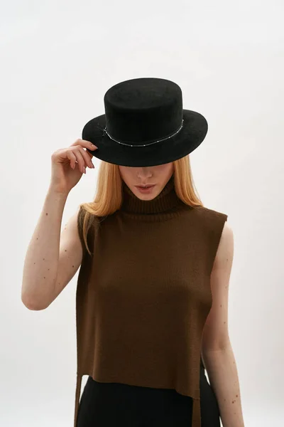 Sottile giovane ragazza caucasica nascondendo il viso sotto il cappello scuro — Foto Stock