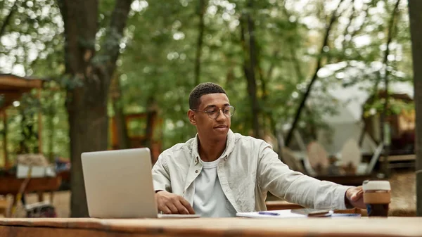 Lächelnder junger afrikanisch-amerikanischer Mann arbeitet am Laptop — Stockfoto