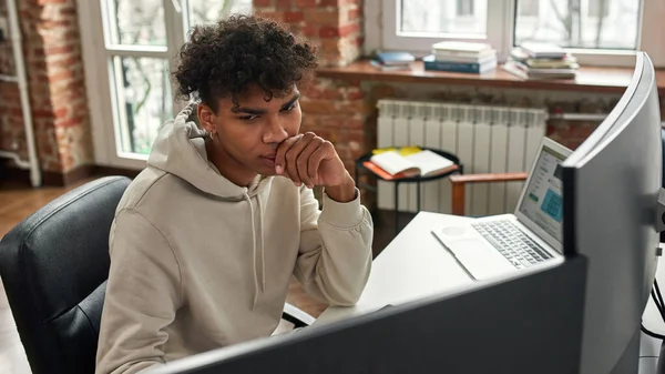 Hochwinkelaufnahme eines jungen Mannes, der mit PC und Laptop online Handel treibt und zu Hause im modernen Wohnzimmer-Büro sitzt — Stockfoto