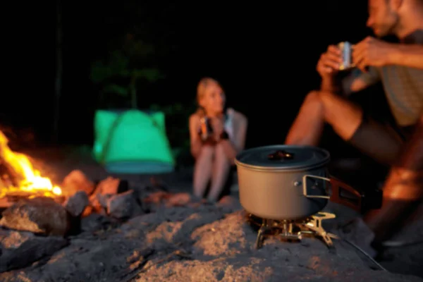 Un par de turistas jóvenes cocinando una comida mientras se relajan juntos cerca de la fogata — Foto de Stock