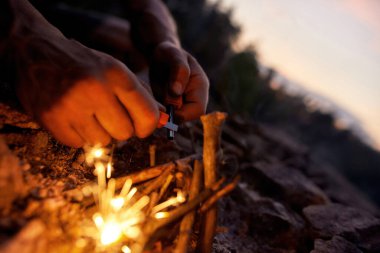 Erkek ellerinin kapalı olması vahşi doğada çakmaktaşı ve çelikten ateş yakıyor.