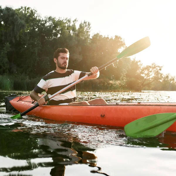 Gericht jongeman kajakken samen met zijn vriend in een meer op een late zomermiddag — Stockfoto