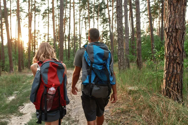 Rear view of tourist backpacks on caucasian couple backs — Stock Photo, Image