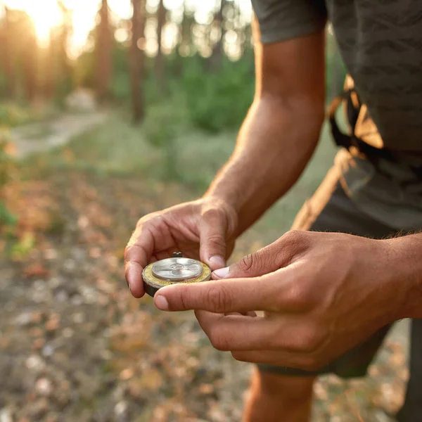 Close up of hands of male tourist holding a compass and looking for direction navigation while hiking in the forest — Stock Photo, Image
