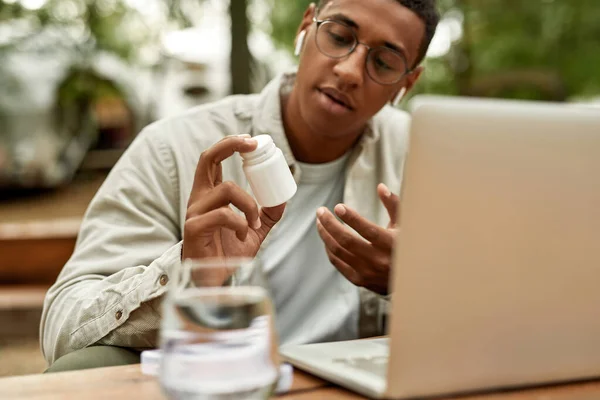 Mann zeigt Pillen-Behälter in Laptop-Bildschirm — Stockfoto