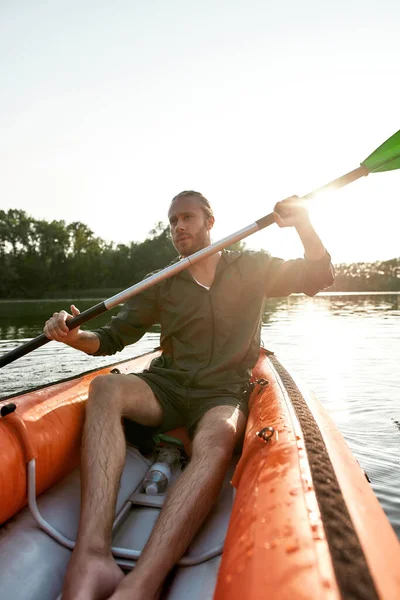 Avontuurlijke jongeman die wegkijkt terwijl hij kajakt in een meer op een zomerdag — Stockfoto