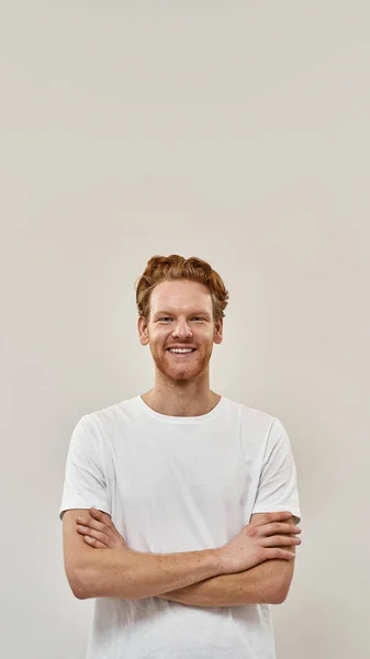 Young redhead man stands with arms folded and looks straight in camera — Stock Photo, Image